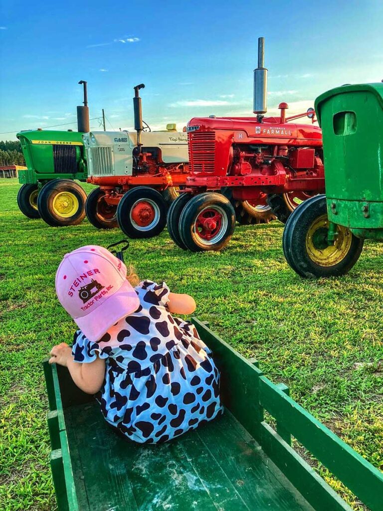 Tractor photo with John Deere, Case, International Farmall tractors, and little girl in pink hat.
